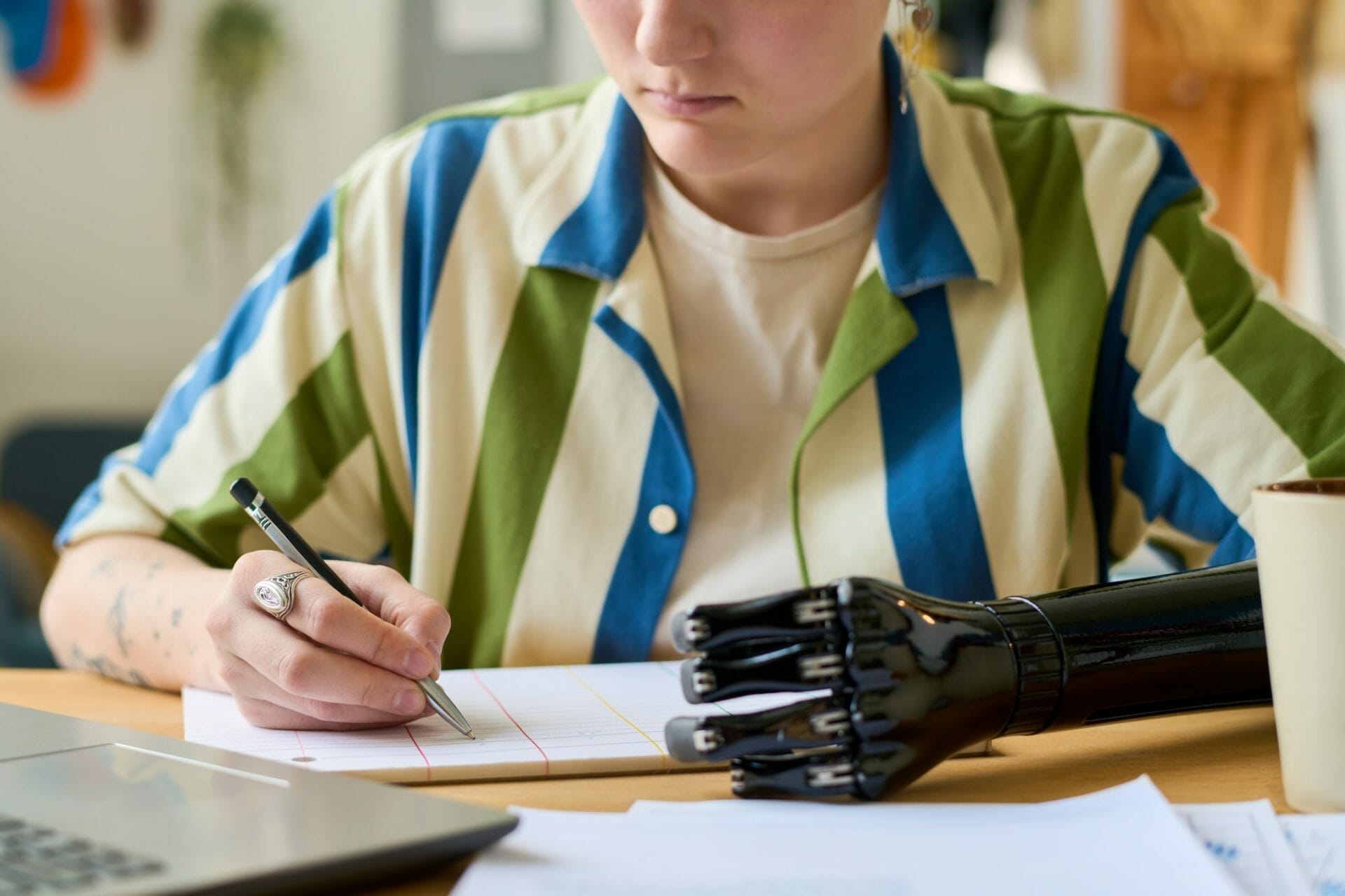 Hands of young businesswoman with arm prosthesis writing down working plan